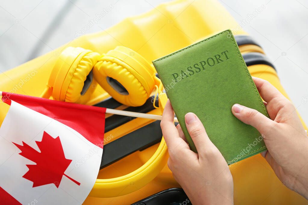 Woman with passport, Canadian flag and luggage, closeup. Travel and immigration concept