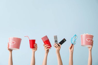 Patlamış mısır, içecek, uzaktan kumanda ve renk arkaplanlı gözlüklü birçok el