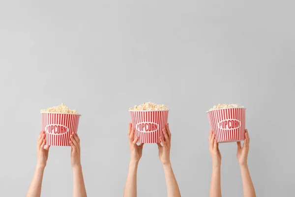 Viele Hände mit Popcorn in Eimern vor grauem Hintergrund — Stockfoto