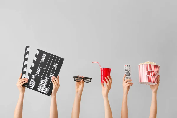Viele Hände mit Popcorn, Getränken, Fernbedienung, Filmklöppel und Brille auf grauem Hintergrund — Stockfoto