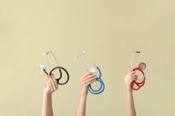 Hands with stethoscopes on color background — Stock Photo, Image
