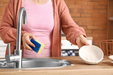 Üst düzey kadın mutfakta bulaşık yıkıyor.