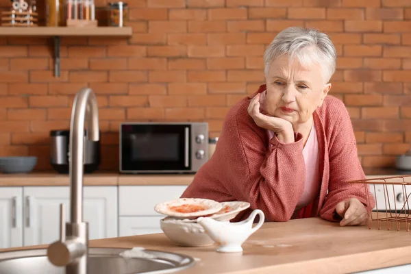 Donna anziana con piatti sporchi in cucina — Foto Stock