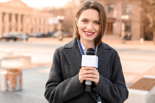 Hermoso periodista con micrófono al aire libre — Foto de Stock
