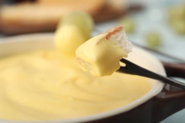 Peynir fondüsüne kızarmış ekmek daldırmak, yakın plan.