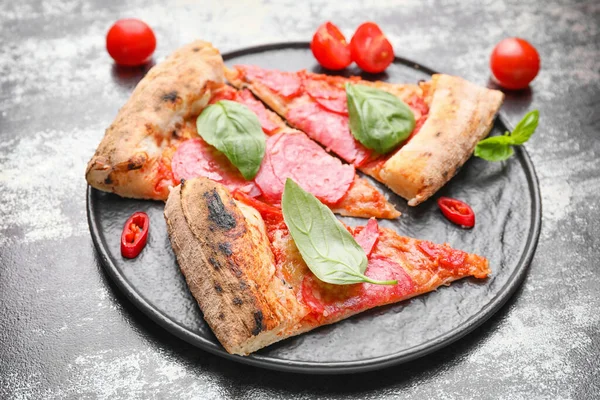 Assiette avec des tranches de pizza savoureuse sur fond sombre — Photo