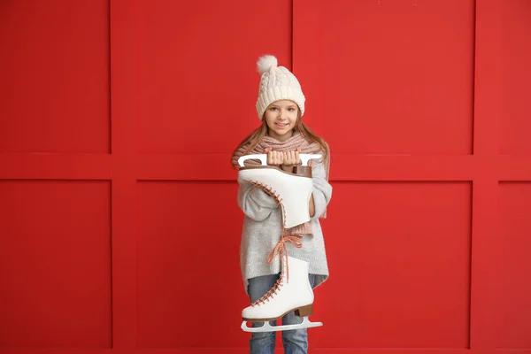 Cute little girl with ice skates on color background — Stock Photo, Image