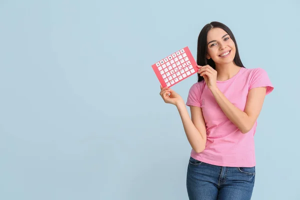 Young woman with menstrual calendar on color background — 스톡 사진