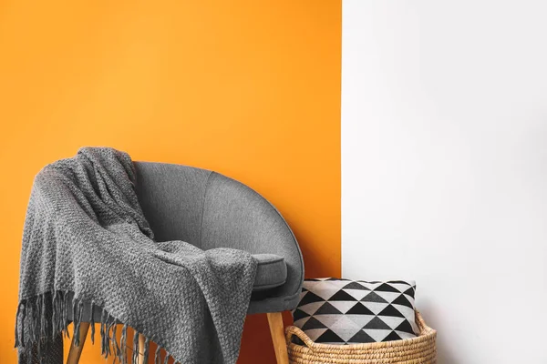 Armchair and basket near color wall in room — Stock Photo, Image
