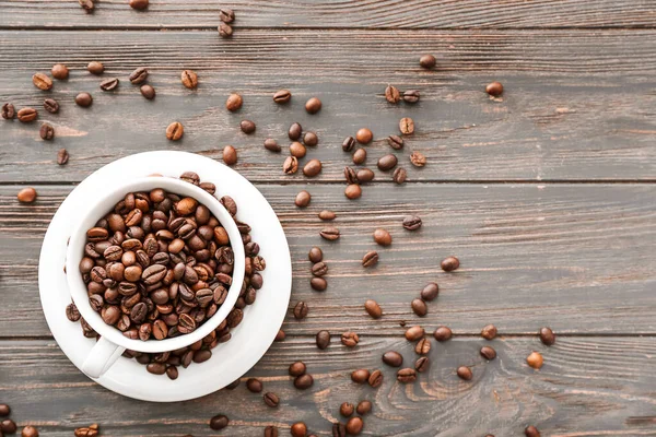 Cup with coffee beans on wooden background — Stock Photo, Image