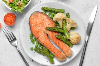Plate with fried salmon and vegetables on table