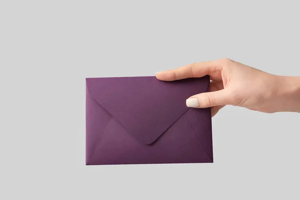 Mão feminina com envelope sobre fundo cinza — Fotografia de Stock