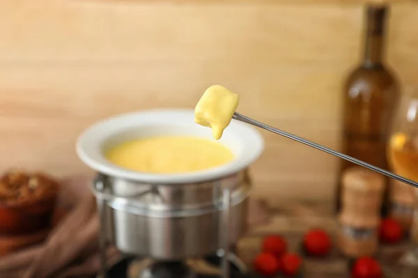 Crouton dipped into cheese fondue, closeup