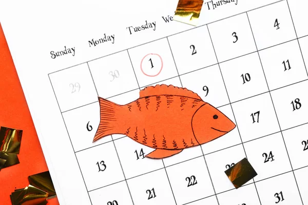 Calendar with marked date of April Fool's Day and paper fish on color background — Stock Photo, Image
