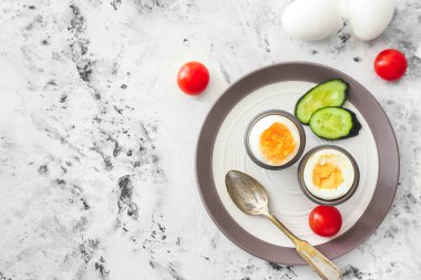 Hafif arka planda lezzetli haşlanmış yumurta ve sebzeli tabak.