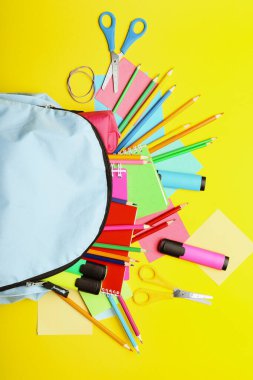 Okul malzemeleri ile renk arka plan üzerinde sırt çantası