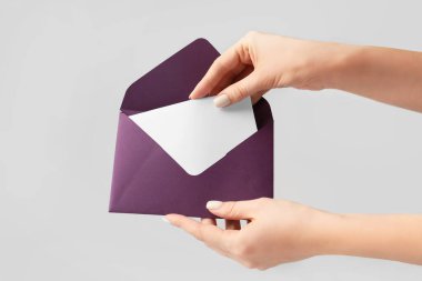 Gri arka planda zarfı olan kadın elleri