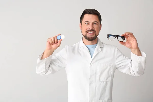 Ophthalmologist with contact lenses and glasses on light background — Stock Photo, Image