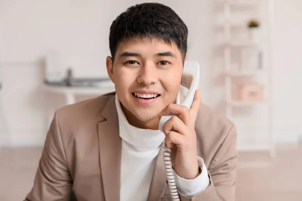 Young Asian businessman talking by phone in office — Stock Photo, Image