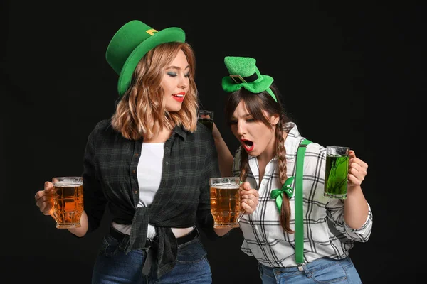 Grappige jonge vrouwen met bier op donkere achtergrond. St. Patrick 's Day viering — Stockfoto