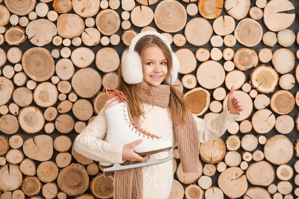 Cute little girl with ice skates on wooden background — Stock Photo, Image