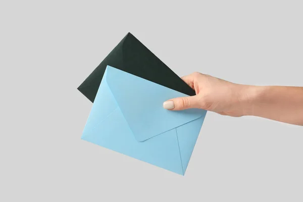 Женская рука с конвертами на сером фоне — стоковое фото