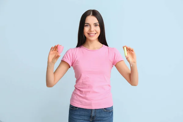 Giovane donna con tazza mestruale e tampone su sfondo di colore — Foto Stock