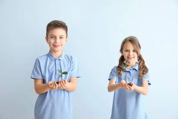 Niños pequeños con plantas y tierra sobre fondo de color. Día de la Tierra —  Fotos de Stock