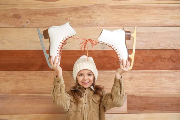 Cute little girl with ice skates on wooden background — Stock Photo, Image