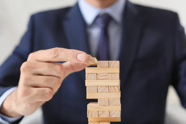 Empresario construyendo torre desde bloques, primer plano. Concepto de planificación, riesgo y estrategia en los negocios — Foto de Stock