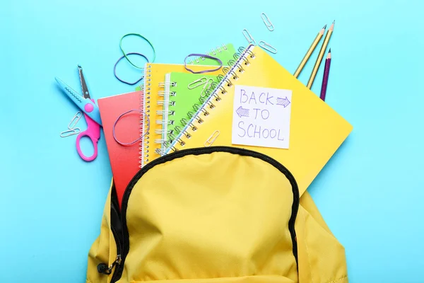 Sac à dos avec fournitures scolaires sur fond de couleur — Photo