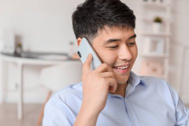 Young Asian businessman talking by phone in office
