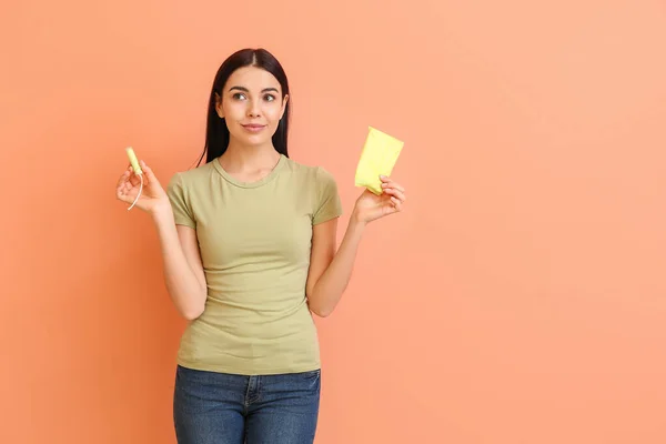 Young woman with menstrual pad and tampon on color background — Stock Photo, Image