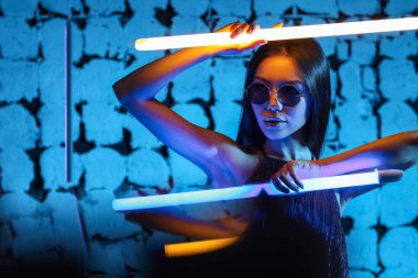Koyu renkli arka planda neon lambaları olan güzel bir kadının tonlu portresi.