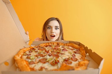 Arka planda lezzetli pizzayla şaşırmış genç bir kadının portresi.