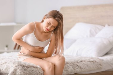 Genç kadın yatak odasında karın ağrısı muzdarip