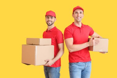Delivery men with boxes on color background