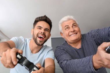 Genç adam ve babası evde video oyunu oynuyorlar.