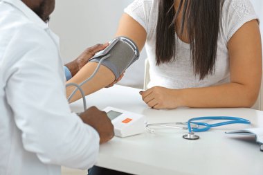 Kadın hastayı klinikte muayene eden erkek kardiyolog.