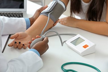 Kadın hastayı klinikte muayene eden erkek kardiyolog.