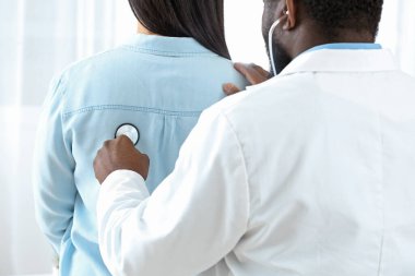 Kadın hastayı klinikte muayene eden erkek kardiyolog.