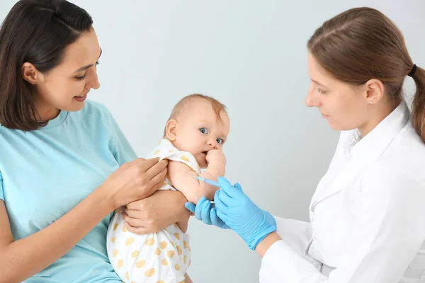 Pediatra szczepiący małe dziecko na jasnym tle — Zdjęcie stockowe