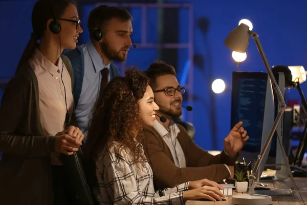 Technical support agents working in office at night