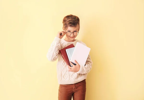 Kleiner Junge mit Büchern auf farbigem Hintergrund — Stockfoto