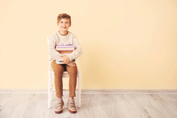 Kitapları olan küçük çocuk renkli duvarın yanında oturuyor. — Stok fotoğraf