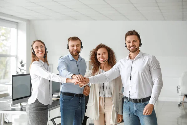 Technical support agents putting hands together in office