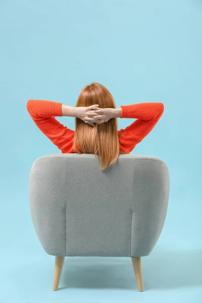 Mooie vrouw ontspannen in fauteuil tegen kleur achtergrond, achteraanzicht — Stockfoto