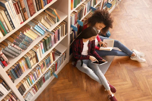 Jovens estudantes se preparando para o exame na biblioteca — Fotografia de Stock