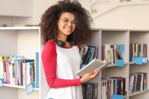 Estudiante afroamericano leyendo libro mientras se prepara para el examen en la biblioteca —  Fotos de Stock