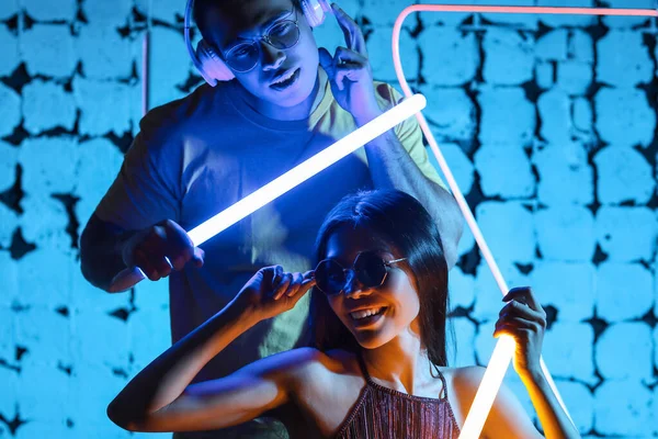 Ritratto tonico di giovane coppia con lampade al neon su sfondo di colore scuro — Foto Stock